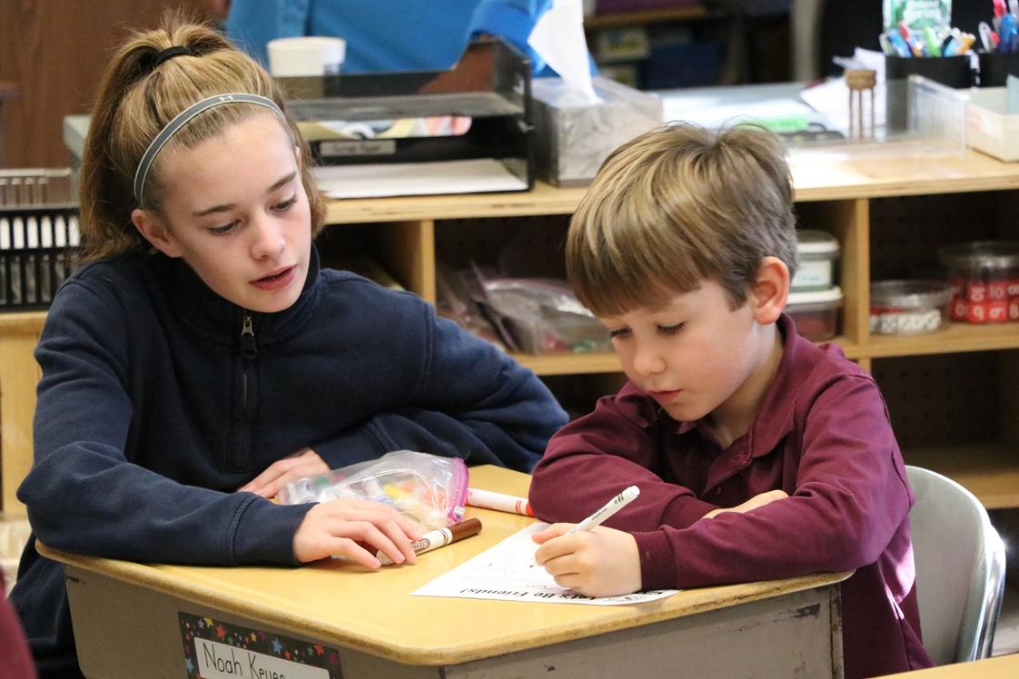 The Imago School Association Photo #1 - One of our 7th grade students helping her 1st grade "Buddy" fill out his profile page to include in his Operation Christmas Child shoe box.