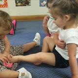 Springdale Road KinderCare Photo #8 - In our center, our children learn to help their friends at infancy. Here Riley is helping Sophia put her shoe back on in the toddler room.