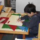 The Happy Childrens Montessori Photo #8 - The Montessori math materials are amazing! This boy is learning addition by working on the addition strip board.