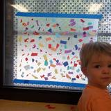 Excelsior KinderCare Photo #6 - One of our Toddlers adding paper to our giant suncatcher.
