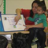 West Chicago KinderCare Photo #5 - Ms. Marisol is teaching her two year olds a new song. In addition to sing it she writes it and draws pictures. Creating a print rich environment is the first step in learning to read and write.