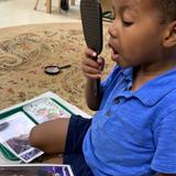 International Montessori School Photo #5 - A toddler student studies facial expressions using a picture card and a mirror.