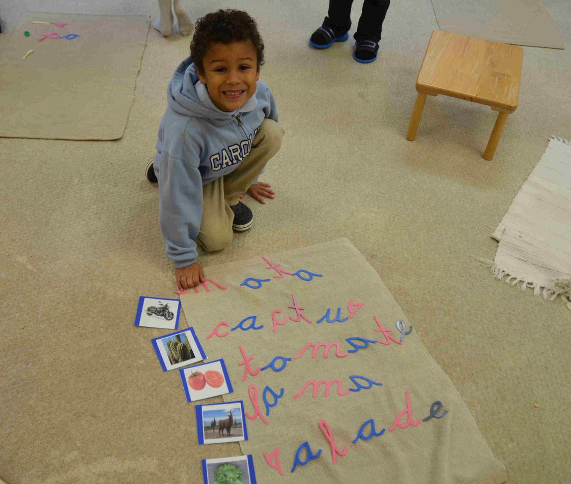 International Montessori School Photo - A 5 year old IMS student using the moveable alphabet to spell the words illustrated on cards.