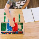 Guidepost Montessori School Photo - The didactic materials in a Montessori classroom allow the child to experience the concepts being taught with both their hands and their mind. This is a child using the stamp game to perform mathematical equations. This tool shows the child the value making it concrete for the child to make sense of the quantity.