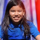 Lake Rose Christian Academy Photo #4 - A Lake Rose Christian Academy student smiles during a classroom moment, holding a fresh apple as she interacts with others.