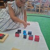 Montessori World School Photo #2 - Hands-on learning in action! Our Primary students build concentration, problem-solving skills, and an early understanding of mathematical relationships while working independently with Montessori materials like the Trinomial Cube.