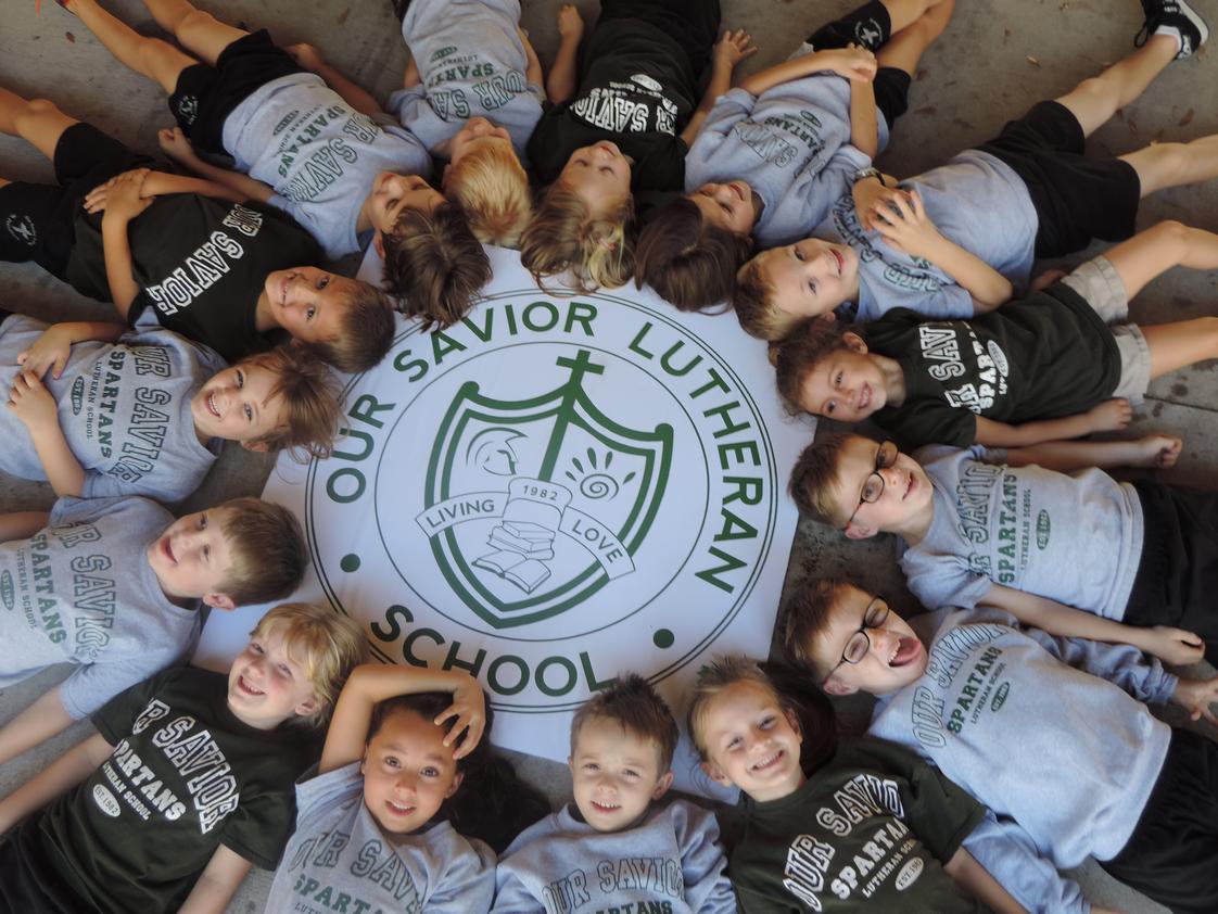 Our Savior Lutheran School Photo - Our Savior's Kindergartners around the crest that represents the strengths from which our school is founded.